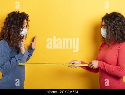 Freunde halten einen Abstand von 1 Meter zwischen ihnen. Konzept der Codiv-19-Regeln zur Vermeidung einer Pandemie. Stockfoto