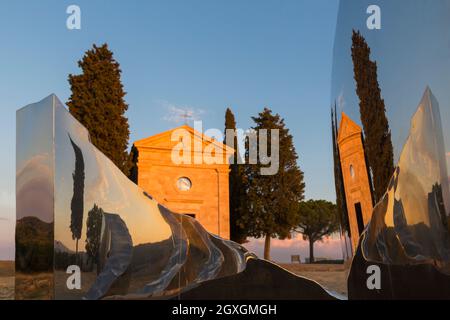 Alte Kirche von Vitaleta mit Bäumen auf beiden Seiten & Abbracio di luce von Helidon Xhixha in San Quirico d'Orcia, in der Nähe von Pienza, Toskana, Italien im September Stockfoto