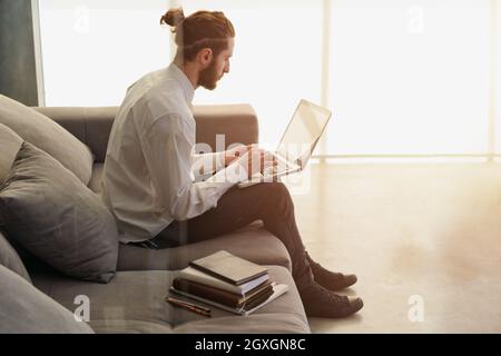 Businessman arbeitet auf dem Sofa mit seinem Laptop Stockfoto