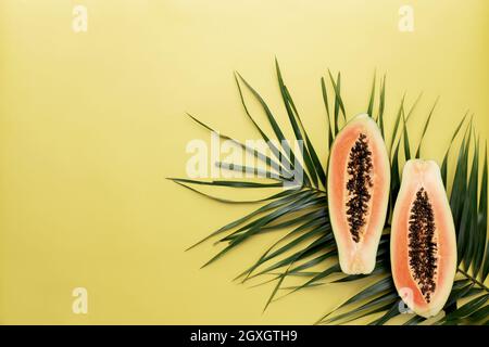 Zwei Hälften frischer Papaya-Tropenfrüchte als gesunde Ernährung Konzept auf dem grünen Palmblatt Stockfoto