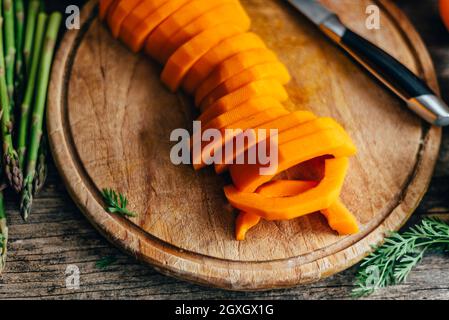 Butternut-Squash-Zubereitung auf einem hölzernen Küchentisch. Kochen von Speisen zum traditionellen Danksagebungsessen. Herbstrezept für Veganer mit Kürbisvege Stockfoto
