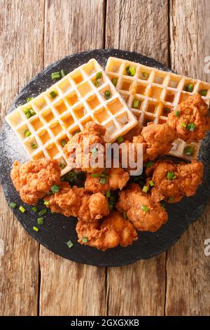 Amerikanisches Essen paniertes Huhn und belgische Waffeln aus der Nähe auf dem Schieferteller auf dem Tisch. Vertikale Draufsicht von oben Stockfoto