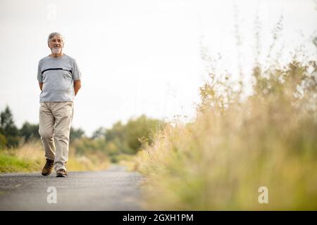 Glücklicher älterer Mann, der an einem warmen Sommertag im Freien läuft Stockfoto