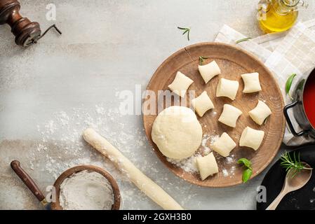 Frische hausgemachte, ungekochte Gnocchi italienische Knödel auf einem bemehlten Holz Verpflegung in einer Küche mit frischen Kräutern Stockfoto