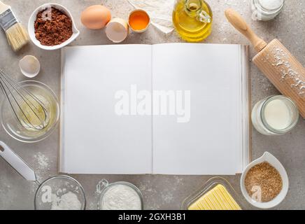 Backdessert Zutaten mit Schokolade, Zucker, Mehl, Eiern, Nudelholz, Butter und leeres Rezeptbuch Hintergrund. Kopierbereich Der Oberen Ansicht. Stockfoto