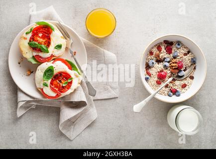 Frühstück mit Haferbrei und Obst, Mozzarella-Sandwich und Saft auf dem Tisch. Gesundes Frühstück. Stockfoto