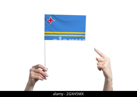 Eine wunderschöne weibliche Hand hält eine Aruba-Flagge, auf der sie den Finger ihrer anderen Hand zeigt, isoliert auf weißem Hintergrund. Stockfoto