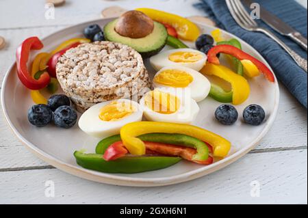 Gesunde, saubere Ernährung und glutenfreie Mahlzeit mit braunem Reiskuchen, Gemüse und Eiern. Farbenfroher Teller mit Essen Stockfoto