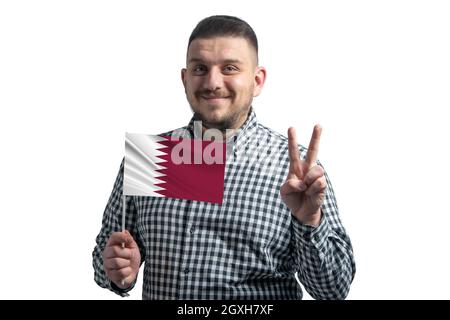 Weißer Kerl hält eine Flagge von Katar und zeigt zwei Finger isoliert auf einem weißen Hintergrund. Stockfoto