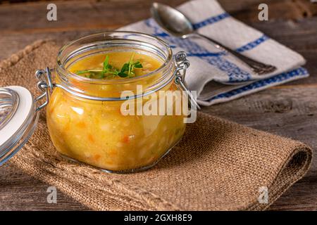 Hausgemachte Suppe oder Eintopf mit Huhn, Gemüse und Kartoffeln in einem Glas auf Holztisch. Stockfoto