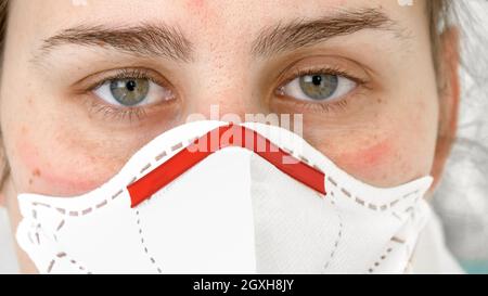 Nahaufnahme Porträt einer Ärztin, die in die Kamera schaut und Schutzbrille, Anzug und Maske aufsetzt. Bekämpfung der globalen Pandemie und Covid-19. Stockfoto