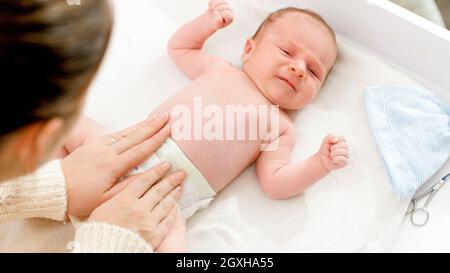 Junge Mutter wechselt unordentliche Windeln zu ihrem neugeborenen Sohn. Stockfoto