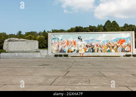 Pjöngjang, Nordkorea - 27. Juli 2014: Kommunistisches Propagandaplakat mit Kim Il Sung in der Nähe des Triumphbogens. Stockfoto