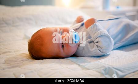 Porträt eines Neugeborenen, das nachts auf dem Bett liegt und Schnuller oder Schnuller saugt. Konzept der Neugeborenen, liebevolle und fürsorgliche Eltern und Familie happin Stockfoto