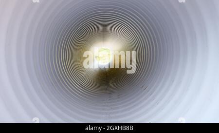 Blick von innen auf die Kunststoff-Wasserleitung. Licht am Ende des Tunnels Stockfoto