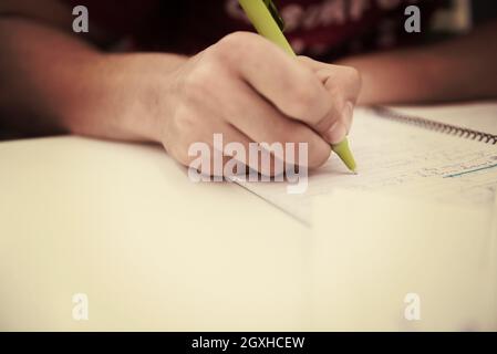 Nahaufnahme eines Studenten Hand unterstreichen ein Dokument auf einem Schreibtisch in der Schule Klassenzimmer Stockfoto