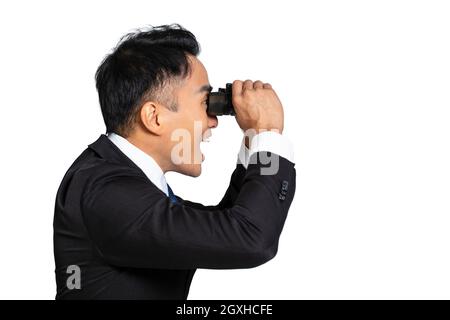 Seitenansicht eines überraschten jungen Geschäftsmannes, der durch ein Fernglas schaute Stockfoto