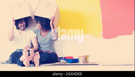 Glückliche junge multiethnischen paar entspannen und spielen mit Kartons nach einen Raum in ihrem neuen Haus auf dem Boden zu malen Stockfoto