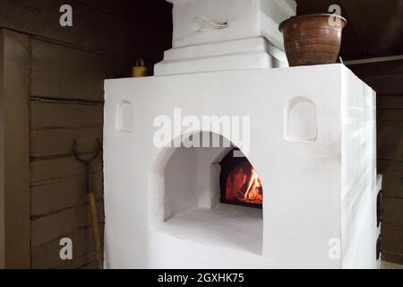 Ein großer russischer Ofen in einem Dorfhaus mit einem Tontopf Stockfotografie