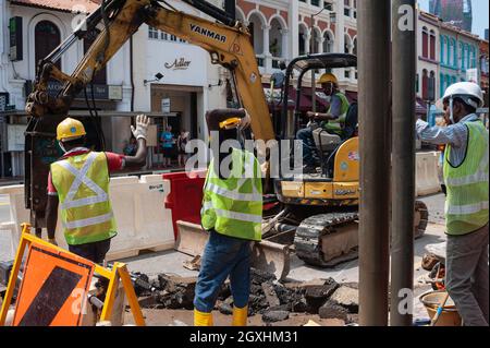 04.04.2018, Singapur, Republik Singapur, Asien - Eine Gruppe südasiatischer Wanderarbeiter repariert das Straßenpflaster einer Straße in Chinatown. Stockfoto