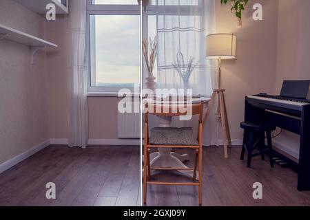 Wohnzimmer mit Sofa und Tisch, vor und nach der Einrichtung. Renovierung mit modernen Möbeln und einem Musikinstrument eines Heims Stockfoto