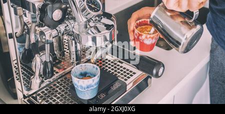 Kaffeemaschine Barista Mann macht Espresso Macchiato Gießen gedämpften Schaum Milch in Tasse zu Hause Banner Panorama Stockfoto