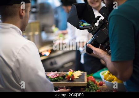 Videographer während einer professionellen Köchinnen und Köche bereiten Mahlzeiten im Hotel oder Restaurant Küche beschäftigt Stockfoto