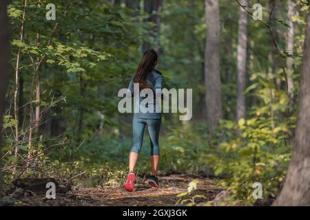 Herbstlauf Athlet Training im Freien in Wald Trail Natur. Läufer joggen von hinten in der Herbstsaison Sportbekleidung Stockfoto