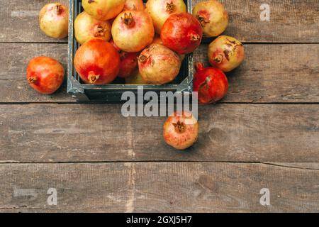 Frische Granatäpfel in einer alten Kiste auf Holzhintergrund Stockfoto