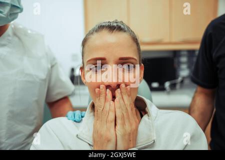 Kaukasischer weiblicher Teenager, der auf einem Arztstuhl sitzt und Angst vor dem Zahnarzt hat, die Zähne gereinigt zu haben Stockfoto