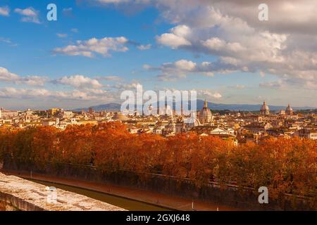 Herbst in Rom. Blick auf die Skyline des historischen Zentrums kurz vor Sonnenuntergang mit dem Tiber, alten Denkmälern, barocken Kuppeln und roten Blättern Stockfoto