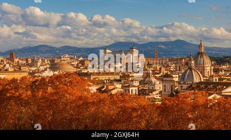 Herbst in Rom. Blick auf die Skyline des historischen Zentrums kurz vor Sonnenuntergang mit alten Denkmälern, barocken Kuppeln und roten Blättern Stockfoto