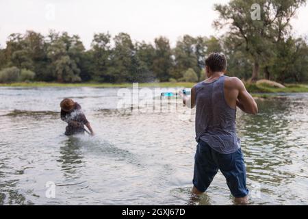 Junge Männer Spaß mit Wasserkanonen und Spritzwasser bei Sonnenuntergang auf dem Fluss Stockfoto