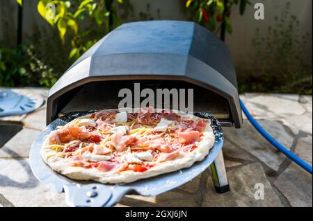 Herstellung von hausgemachter Pizza in tragbaren Hochtemperatur-Gas-Pizza-Ofen. Köstliche Pizza ist Backen in Gas-Ofen Ofen für hausgemachte neapolitanische Pizza. Spec Stockfoto