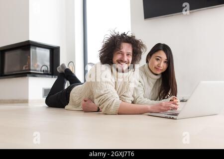 Junge schöne multiethnischen paar mit einem Laptop und Online-shopping zu Hause auf dem Boden Stockfoto