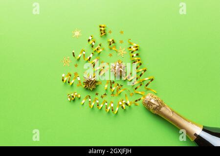 Kreative, flache Lay-Komposition mit einer Flasche Champagner und Platz für Text auf farbigem Hintergrund. Champagner-Flasche mit bunten Party-Streamer. Urlaub Stockfoto