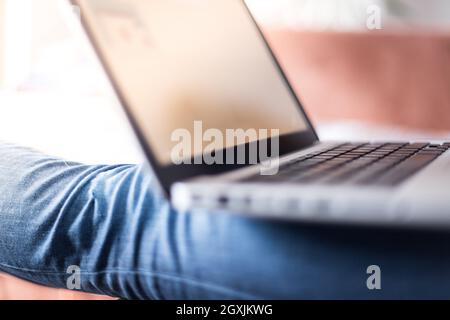 Mädchen mit violetten Fingernägeln benutzt ihren Laptop zu Hause auf der Couch Stockfoto