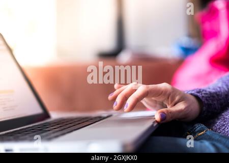 Mädchen mit violetten Fingernägeln benutzt ihren Laptop zu Hause auf der Couch Stockfoto