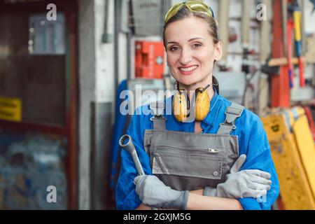 Eine Arbeiterin in ihrer Metallwerkstatt posiert mit Werkzeugen für die Kamera Stockfoto