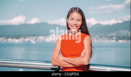 Asiatische Geschäftsfrau zuversichtlich multirassische Geschäftsfrau Porträt lächelnd mit gekreuzten Armen in rot oben außerhalb in Vancouver, Kanada Stockfoto