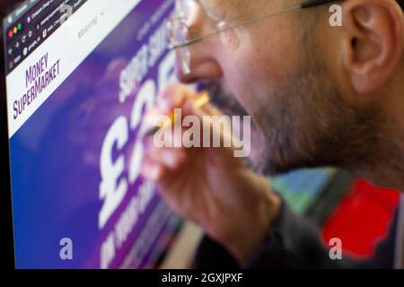 Mann, der auf der Internet-Website von Geld Supermarkt Moneysupermarket Stockfoto