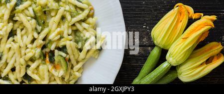 Trofie, italienische Pasta mit Zucchini und Zucchini auf dunklem Holzhintergrund Stockfoto