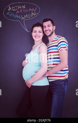 Junge schwangere paar Gedanken über Namen für Ihr ungeborenes Baby und sie schreiben auf eine Schwarze Schiefertafel Stockfoto