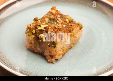 Syrischer Grießkuchen mit Zuckersirup, leckerer Harisse auf blauer Keramikplatte, syrisches Dessert Stockfoto