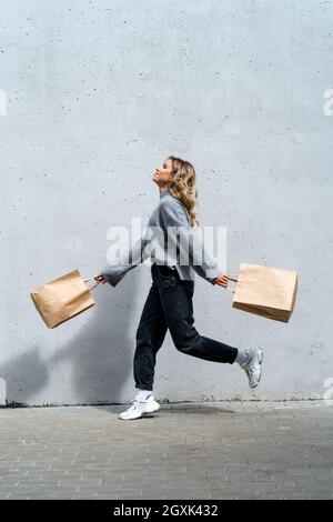 Frau, die mit zwei Einkaufstüten die Straße entlang läuft Stockfoto