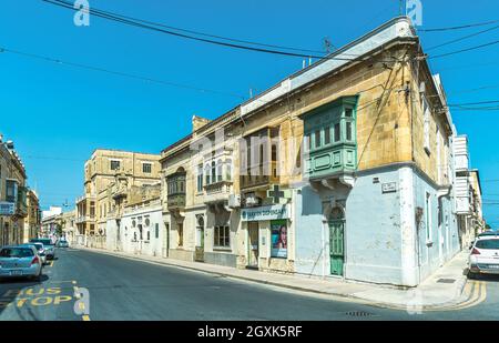 Typisch maltesische Wohnarchitektur mit bunten Holzfrontüren, Lamellenfenstern und geschlossenen Holzbalkonen - Tarxien, Malta. Stockfoto