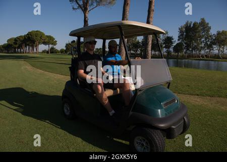Golf-Spieler fahren Wagen mit Kurs auf schönen Morgen Sonnenaufgang. Freunden zusammen Spaß und Entspannung im Urlaub. Stockfoto