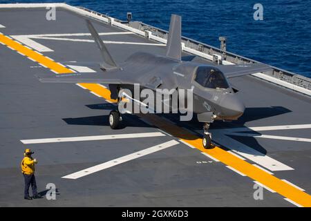 Ein U.S. Marine Corps F-35B Lightning II Stealth-Kampfjet mit Marine Fighter Attack Squadron 242 führt während gemeinsamer Einsätze am 3. Oktober 2021 vor der japanischen Küste eine vertikale Landung auf dem Flugdeck des japanischen Hubschrauberflugzeuges JS Izumo durch. Die Landung ist die erste F-35B Lightning II-Kampfflugzeug-Operation an Bord eines japanischen Schiffes. Stockfoto