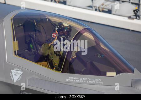 U.S. Marine Corps LT. Col. Robert Gyette, Executive Officer des Marine Fighter Attack Squadron 242, hält nach der Landung eines F-35B Lightning II Stealth-Kampfjets auf dem Flugdeck des japanischen Hubschrauberflugzeuges JS Izumo während gemeinsamer Operationen am 3. Oktober ein Schiffsfeld hoch, 2021 vor der japanischen Küste. Die Landung ist die erste F-35B Lightning II-Kampfflugzeug-Operation an Bord eines japanischen Schiffes. Stockfoto