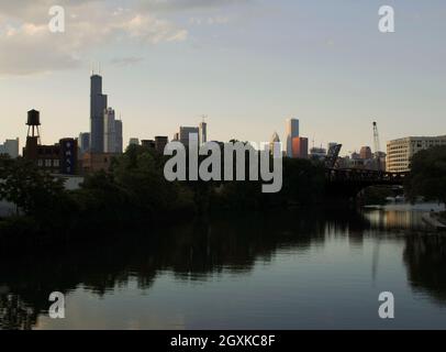 USA, Bundesstaat Illinois, Chicago. Blick auf den Chicago River bei Sonnenuntergang, während er durch ein Industriegebiet führt. Im Hintergrund die Wolkenkratzer der Innenstadt. Bundesstaat Illinois. Stockfoto